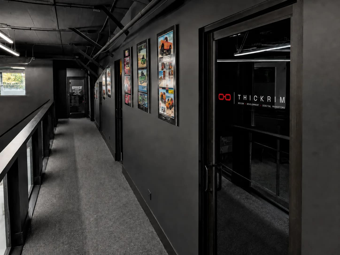 The THICKRIM studio: framed client work along the corridor to the studio door.